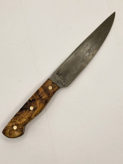 Ein hochwertiges Damastmesser mit einem eleganten Holzgriff aus Olivenholz liegt auf einer dunklen Oberfläche. Die Klinge zeigt die charakteristische wellenförmige Musterung des Damaststahls.
