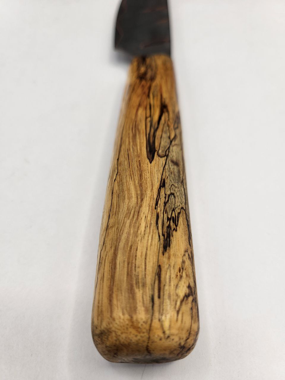 Detailaufnahme vom handgeschmiedeten Jausen und Gemüsemesser mit Damaststruktur